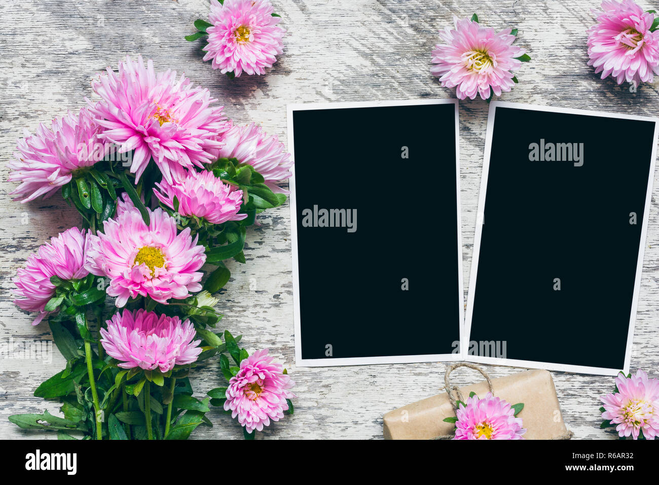 blank photo frames with beautiful bouquet of pink aster flowers and gift box to put your pictures. mock up. layout. holiday or wedding background. top Stock Photo