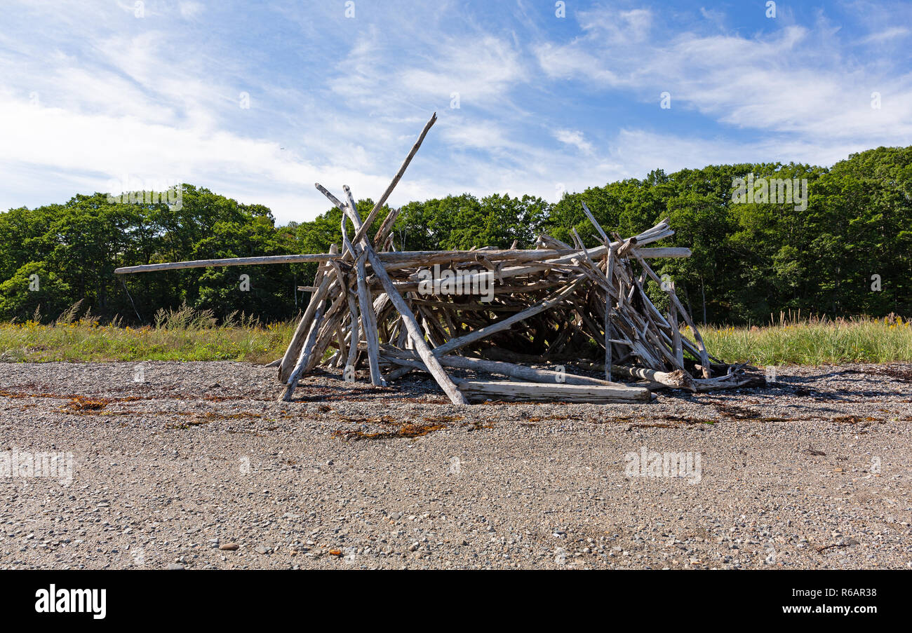 Driftwood sticks arranged in a haphazard lean to on a beach in Maine. Stock Photo
