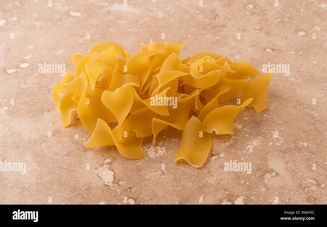 A portion of no yolk wide pasta on a beige mottled counter top. Stock Photo
