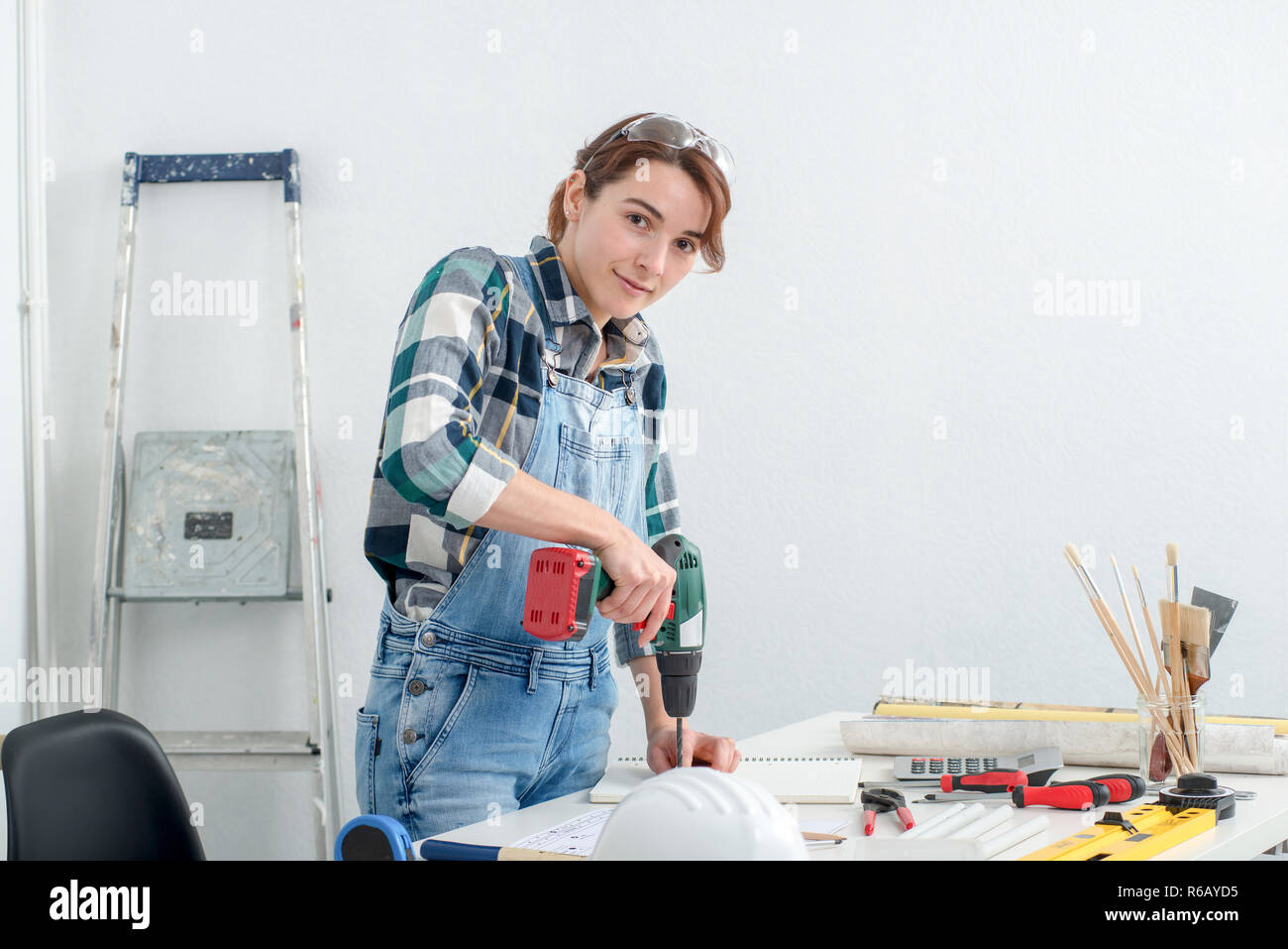 pretty young smiling woman using cordless drill Stock Photo