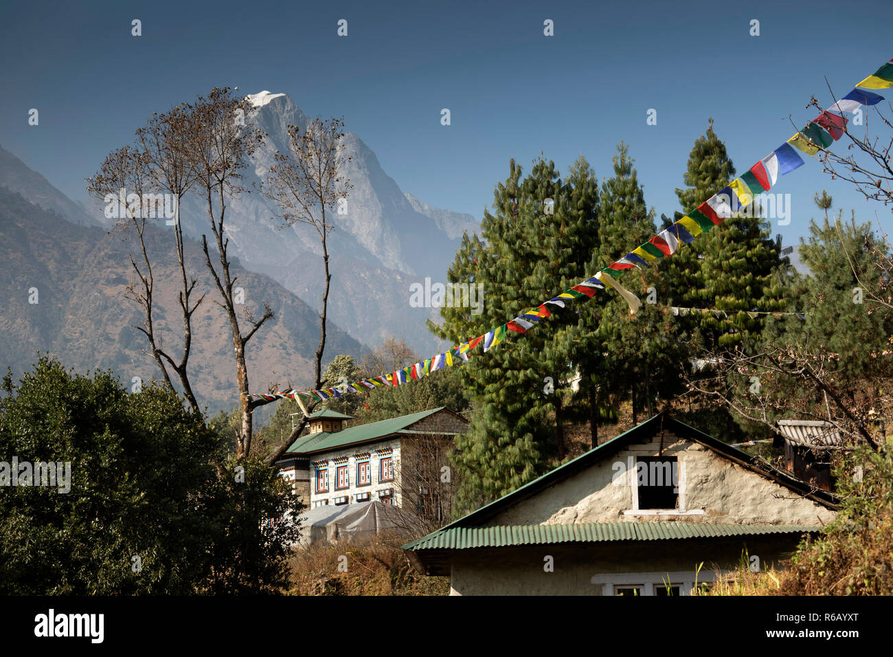 Nepal, Lukla, Chheplung, village houses below prayer flags and snow capped peak of Solu Khumbu Stock Photo