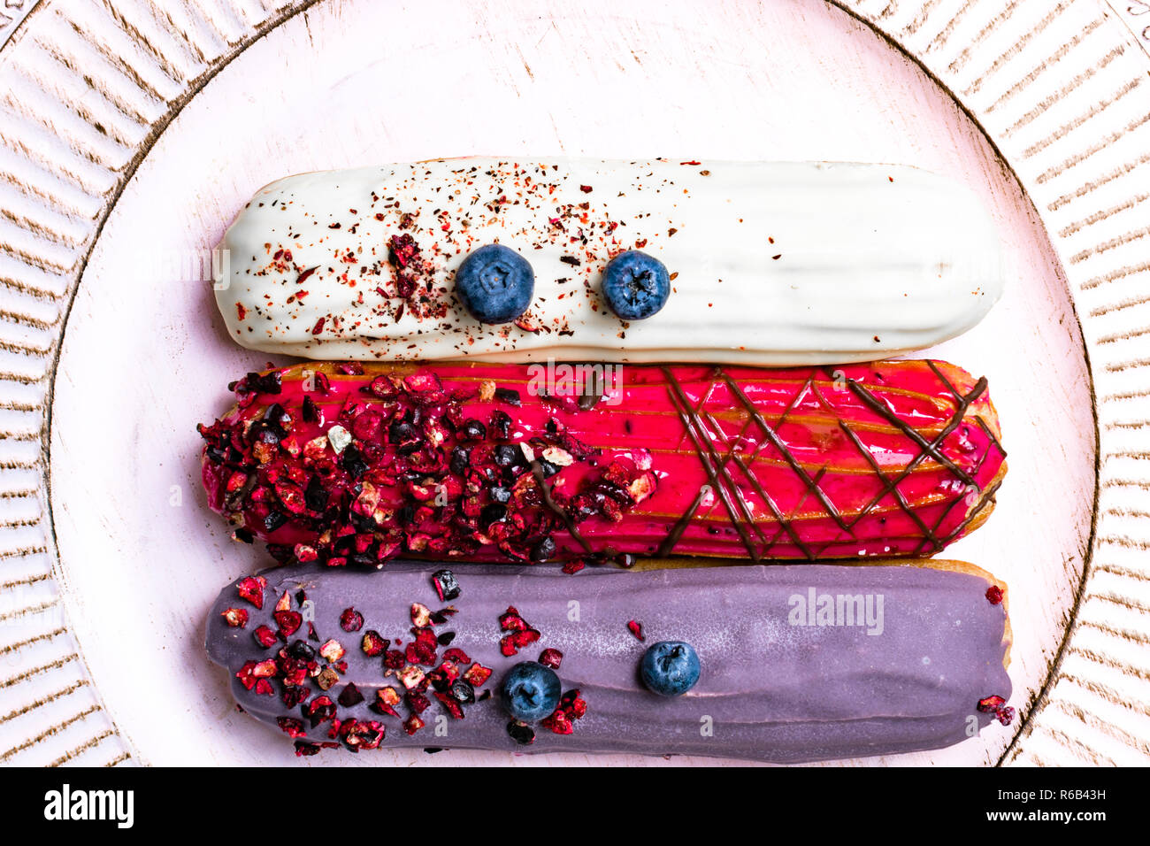 colorful eclairs red white violet with blueberry, raspberry, isolated on white background Stock Photo