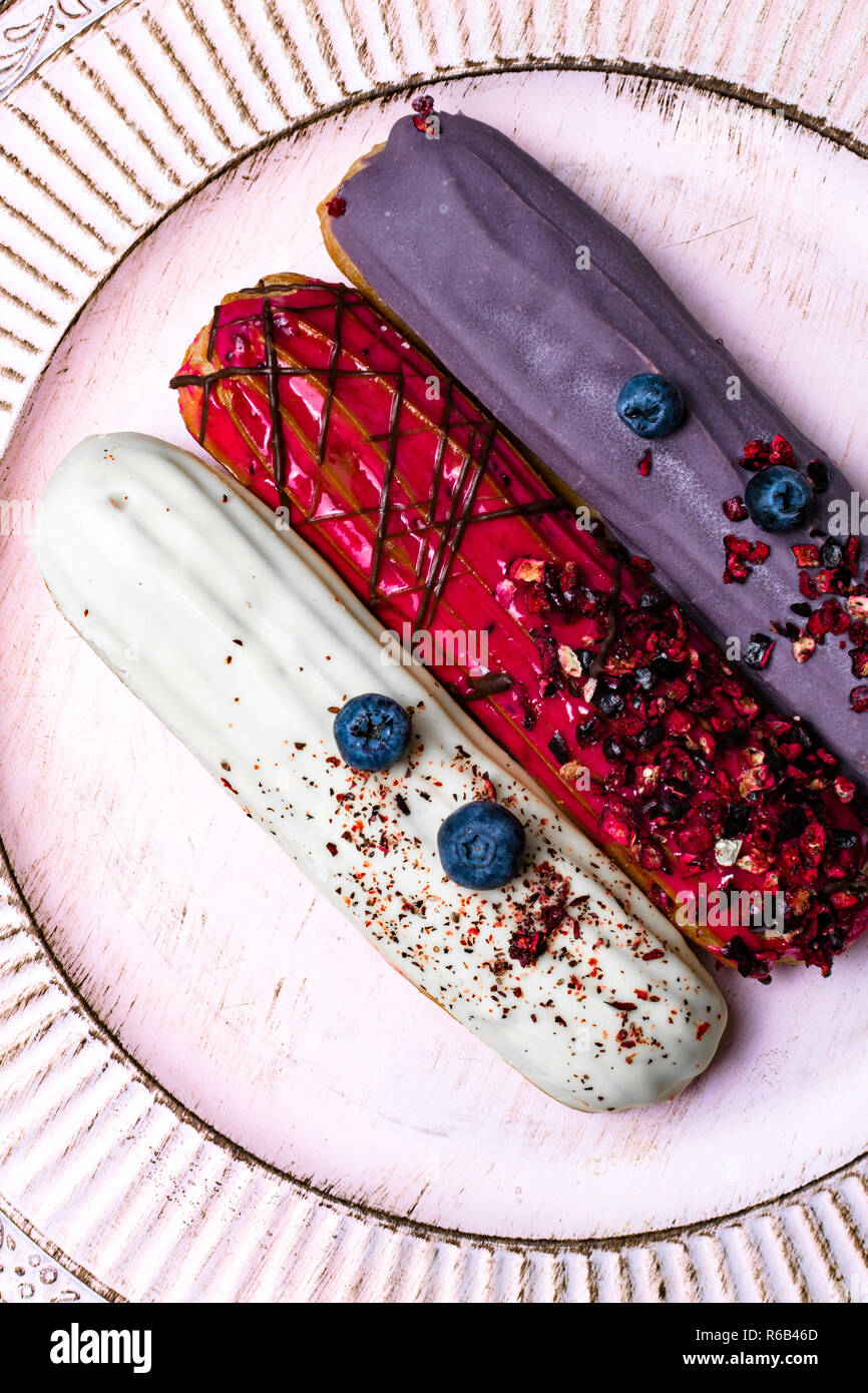 colorful eclairs red white violet with blueberry, raspberry, isolated on white background Stock Photo