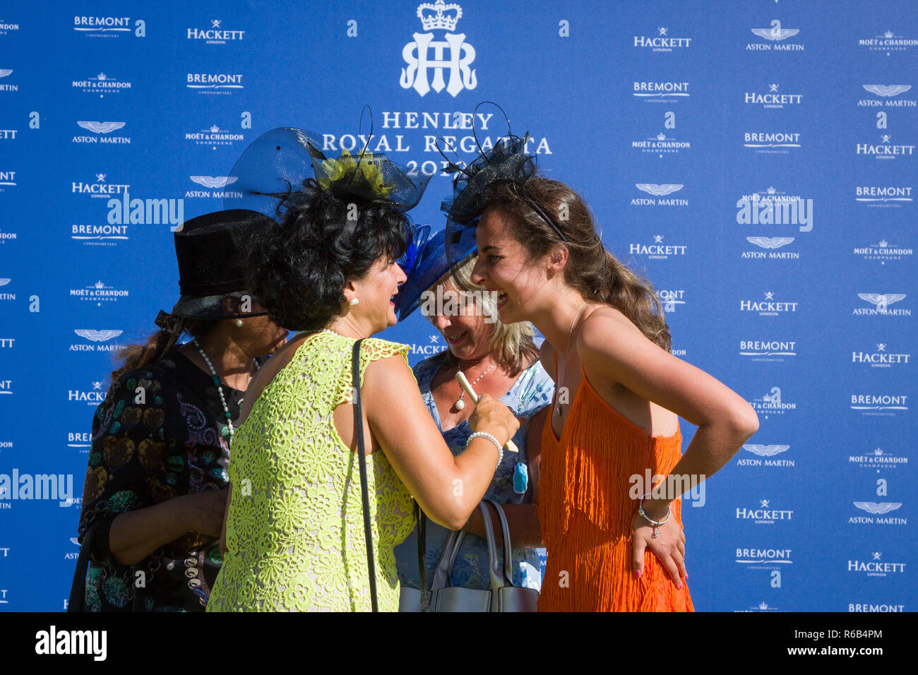 Guests enjoy a joke in front of hte official sponsors board at Henley Royal Regatta Stock Photo