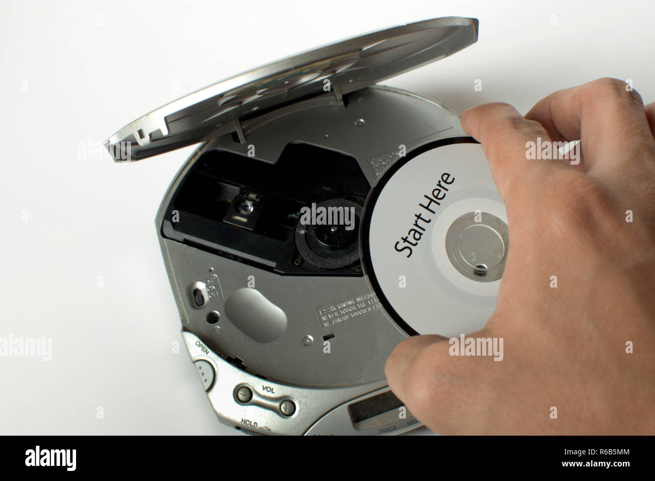 A man is inserting a cd in a cd player with a start here message Stock  Photo - Alamy