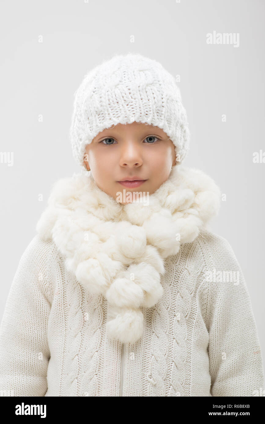 Portrait of a cute little girl in white winter clothes. Looking at ...