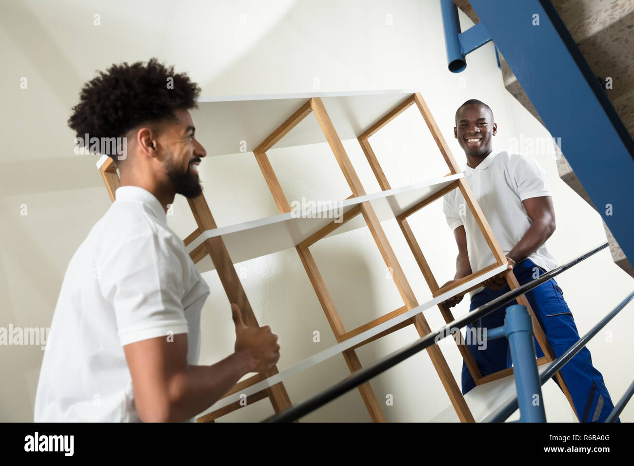 Two Male Movers Carrying The Empty Shelf At Home Stock Photo Alamy