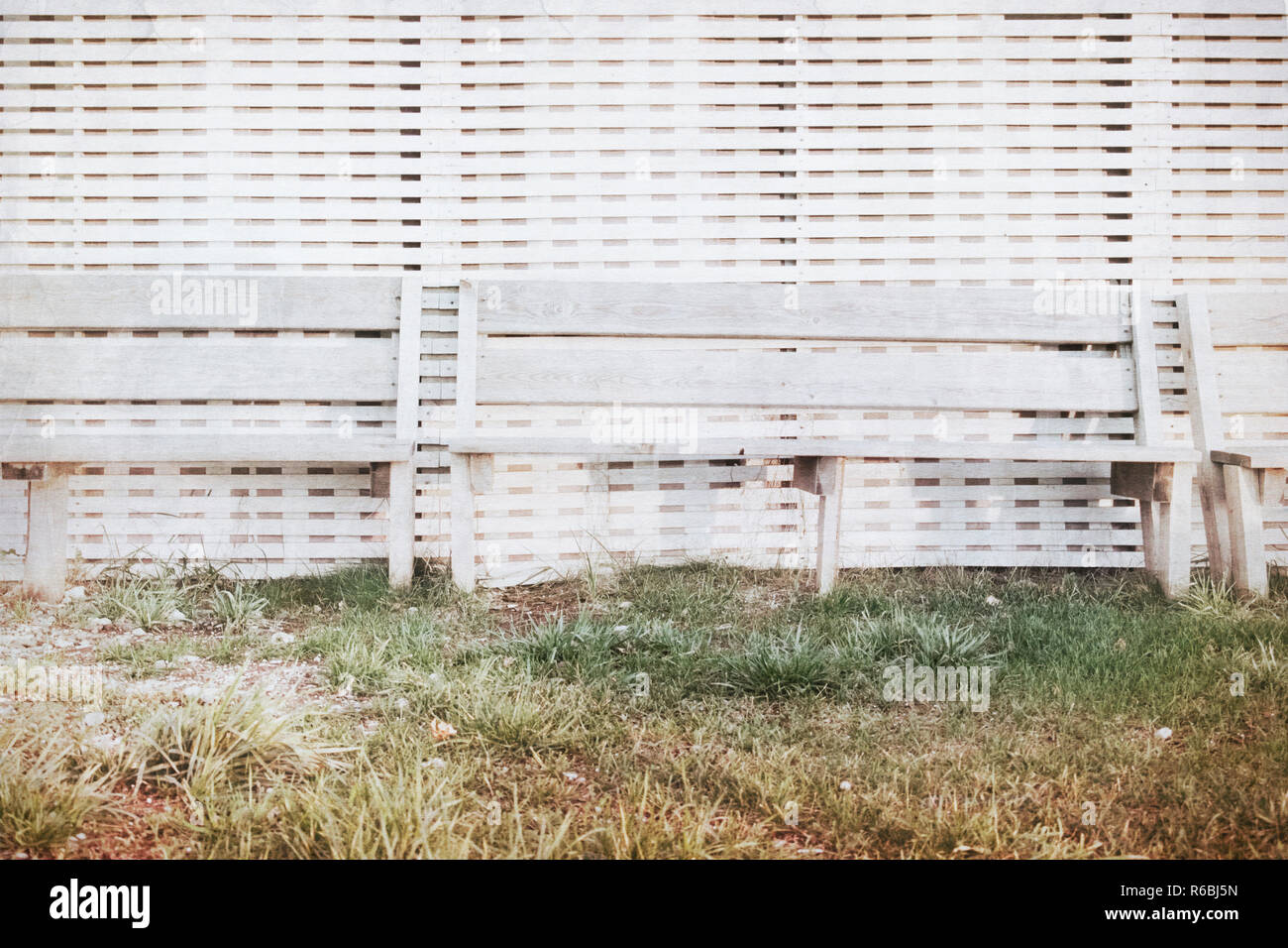 Bench stand at a wall from white colored boards at sunset by the sea Stock Photo