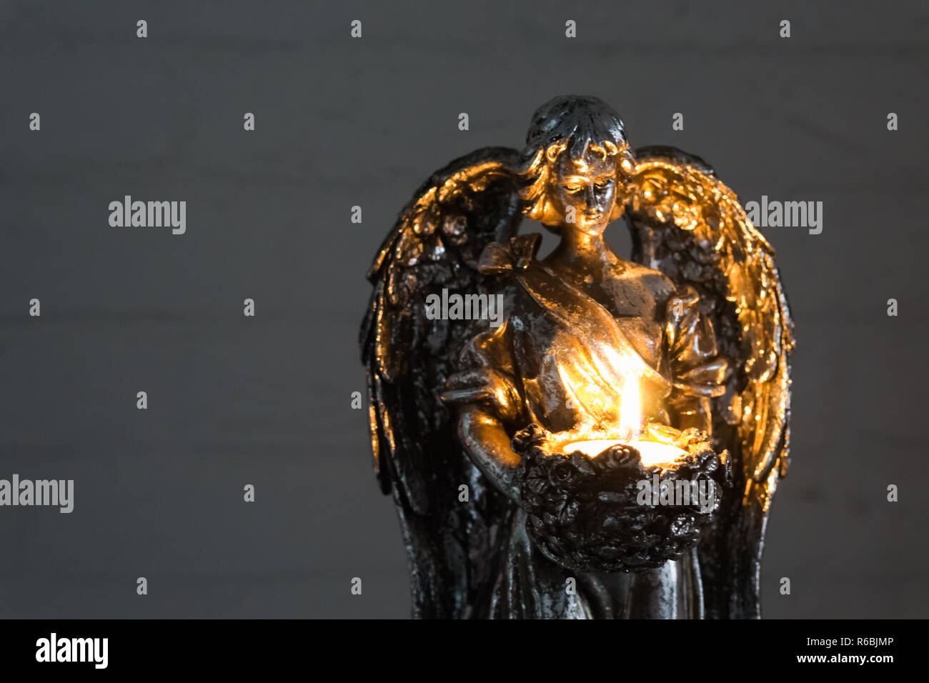 silver angel statue holding a burning candle in closeup, christmas and