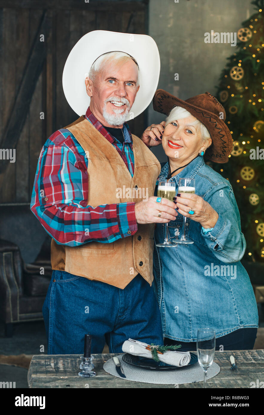 Senior couple celebrating New year's, having champagne, lighting and christmas tree on background Stock Photo