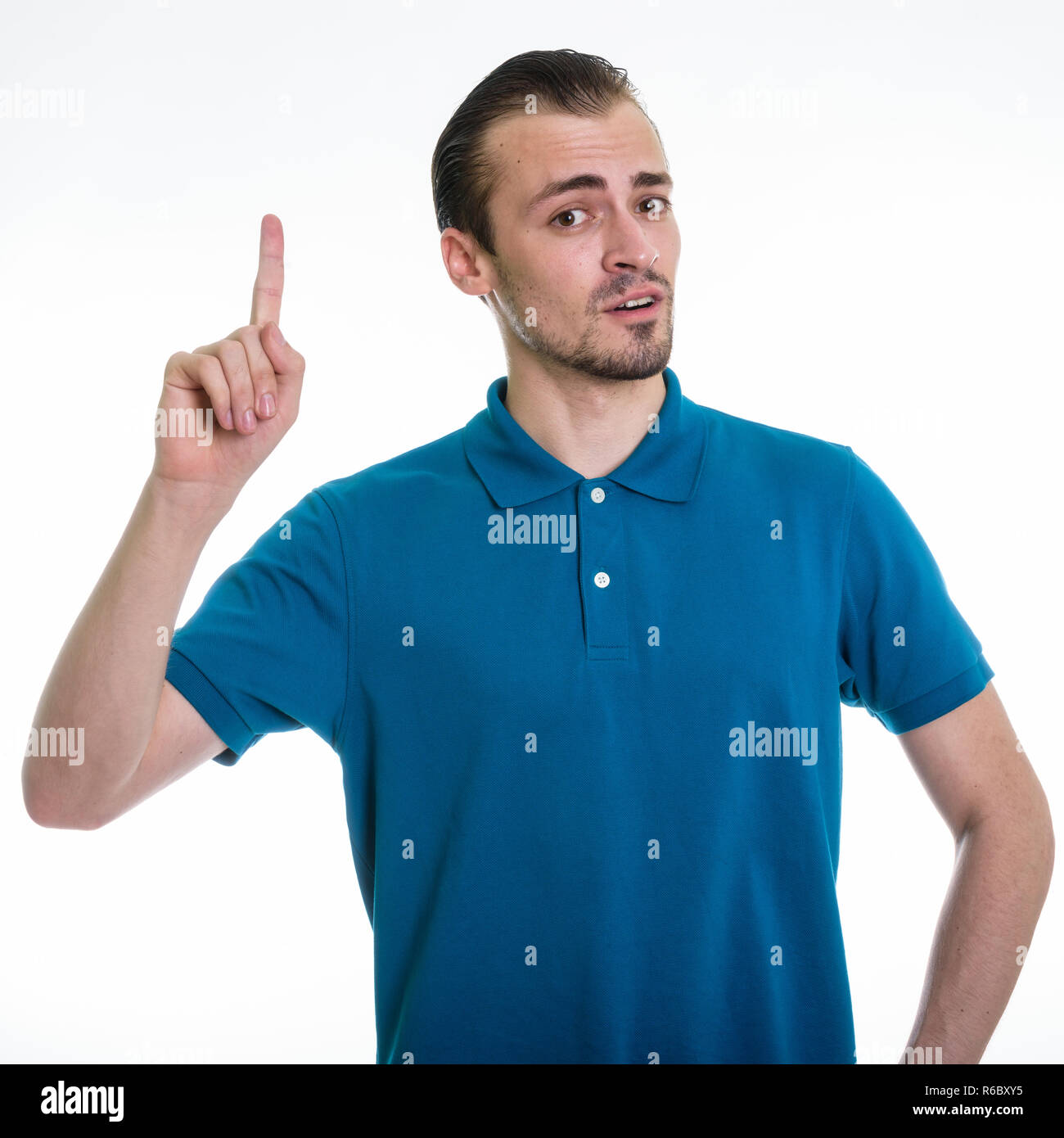 Studio shot of young bearded man pointing finger up against whit Stock Photo
