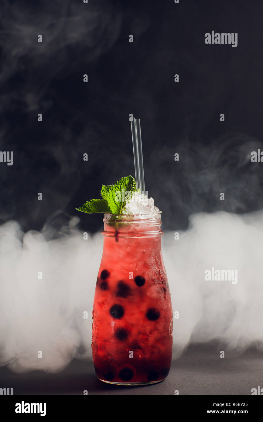 dark and stormy rum cocktail with Strawberry against background smoke. Stock Photo