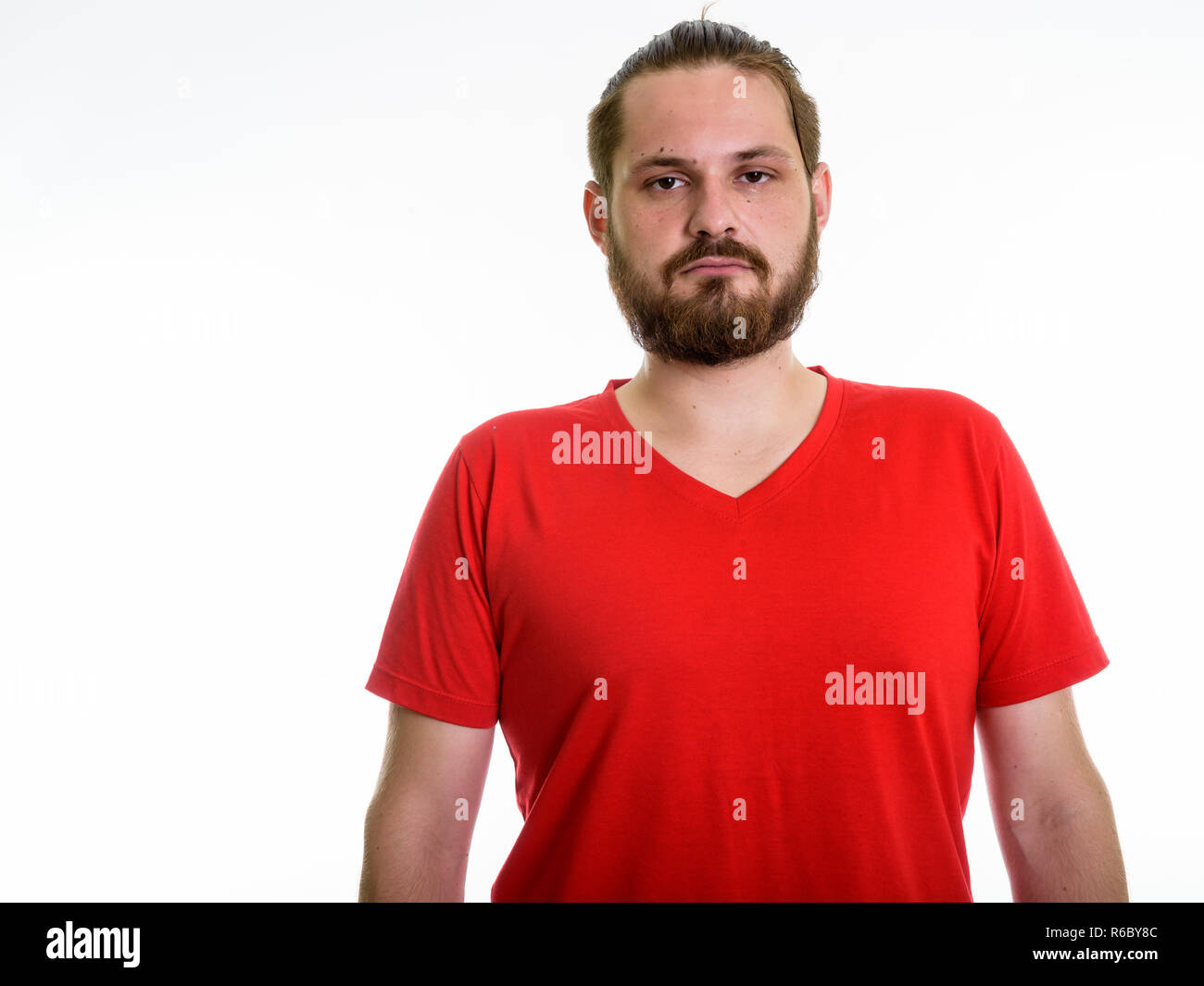 Studio shot of young bearded man with hair tied against white ba Stock Photo