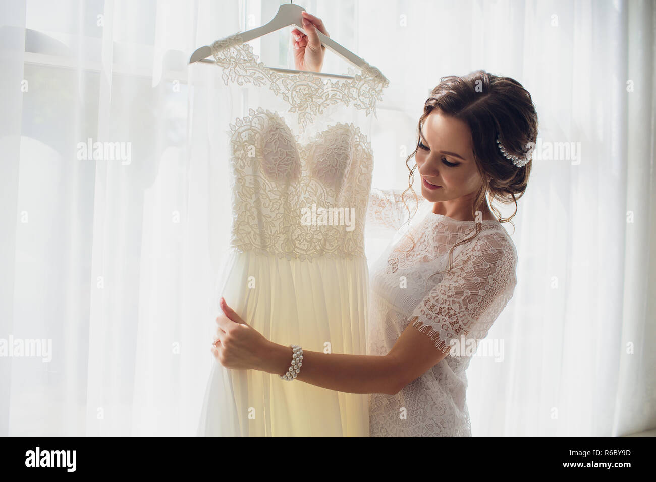Pretty bride in silk dressing gown and lacy veil holding