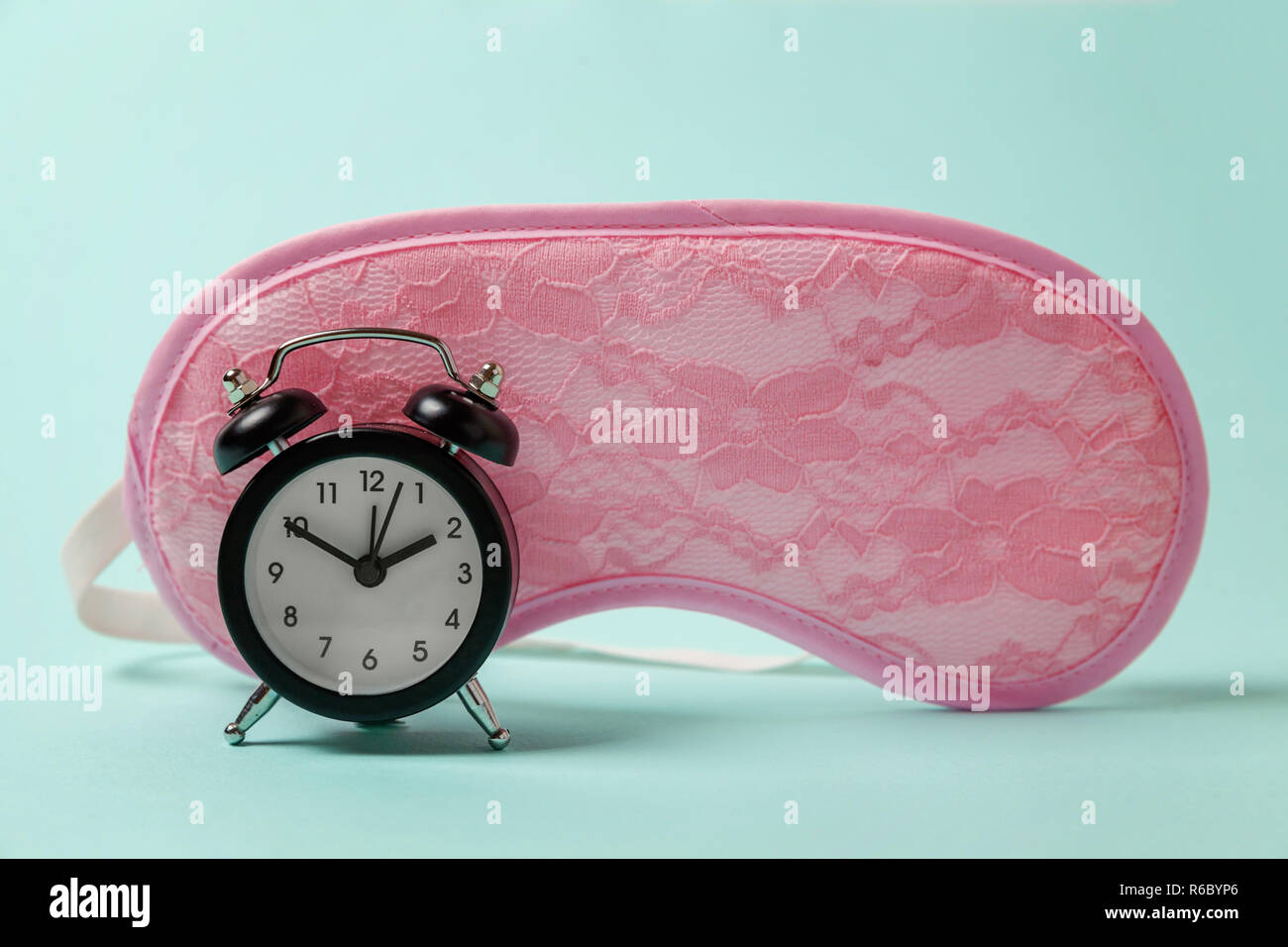 Sleeping eye mask, alarm clock isolated on blue pastel colourful trendy background. Do not disturb me, let me sleep. Rest, good night, siesta, insomnia, relaxation, tired, travel concept Stock Photo