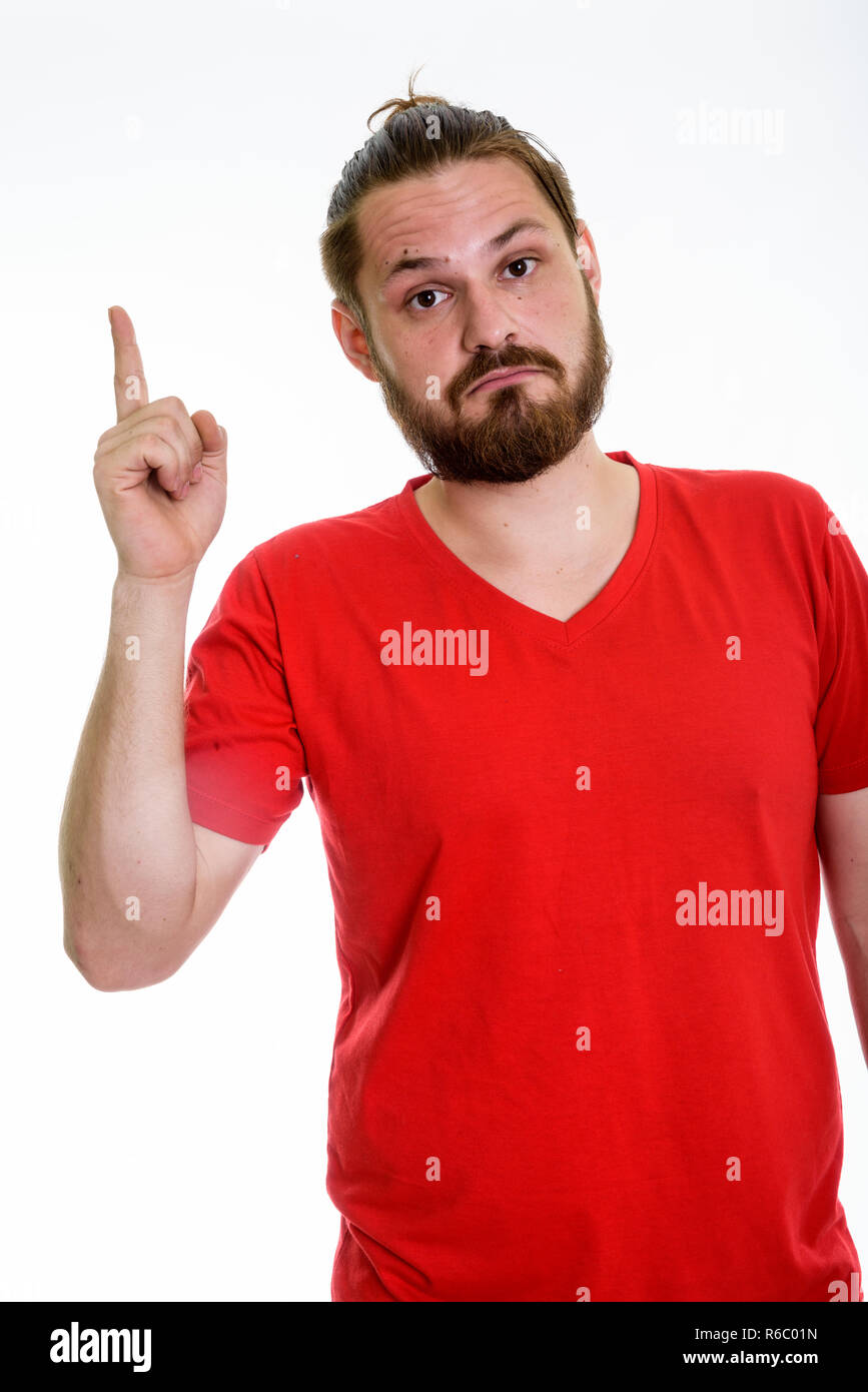 Studio shot of young bearded man pointing finger up with hair ti Stock Photo
