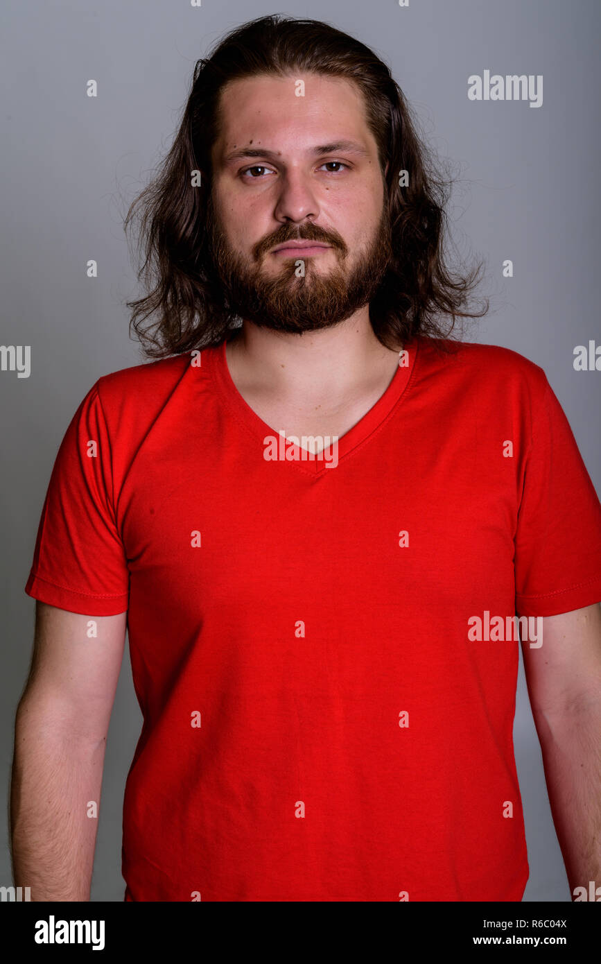 Studio shot of young bearded man with long hair against gray bac Stock Photo