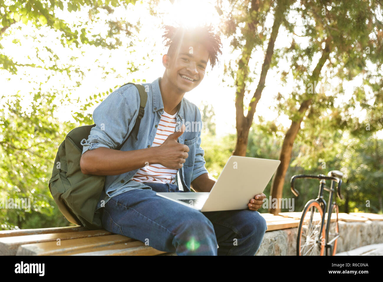 Image of handsome emotional young african guy in park outdoors using ...