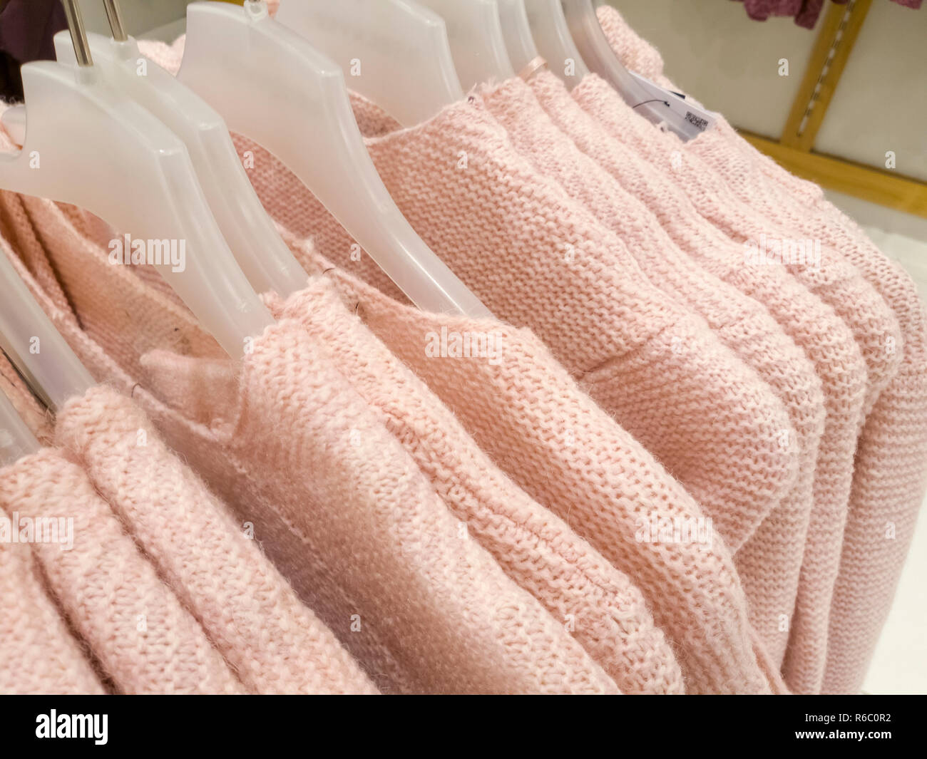 Knitted woolen sweaters on a hanger in store Stock Photo