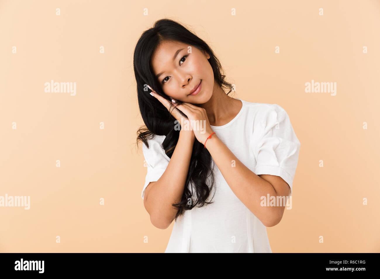 Portrait of a smiling young asian woman isolated over beige background ...