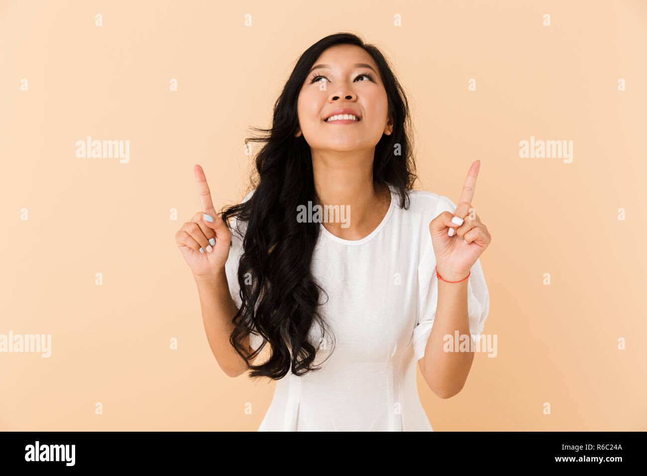 Portrait of a joyful young asian woman isolated over beige background ...