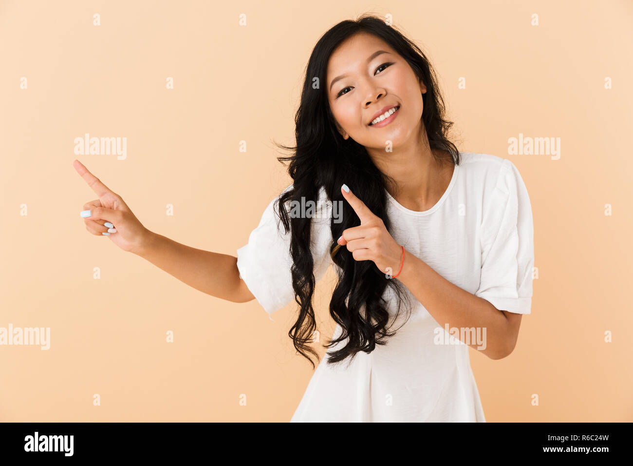 Portrait of a happy young asian woman isolated over beige background ...