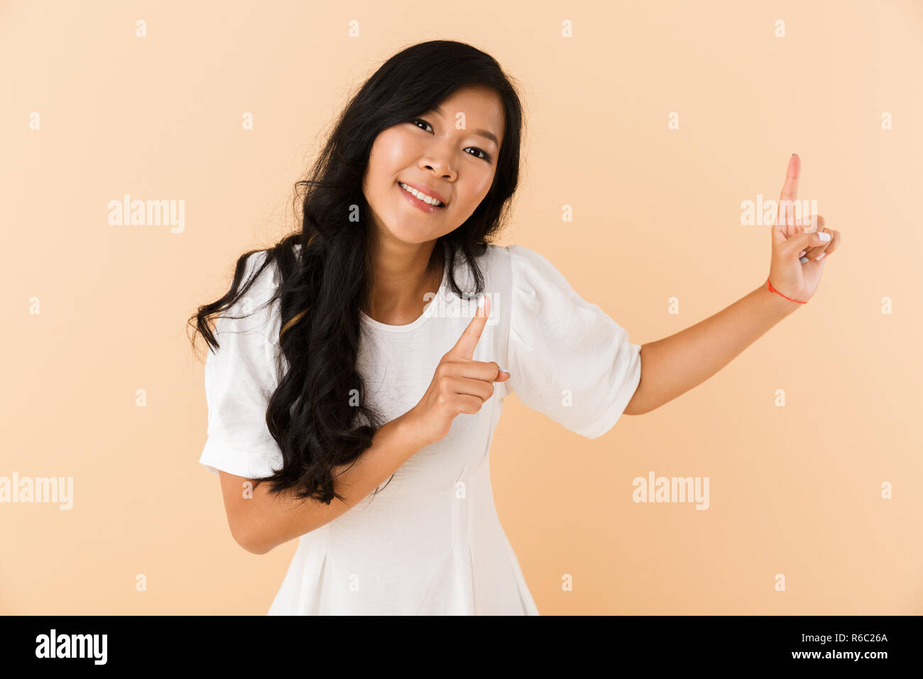 Portrait of a lovely young asian woman isolated over beige background ...