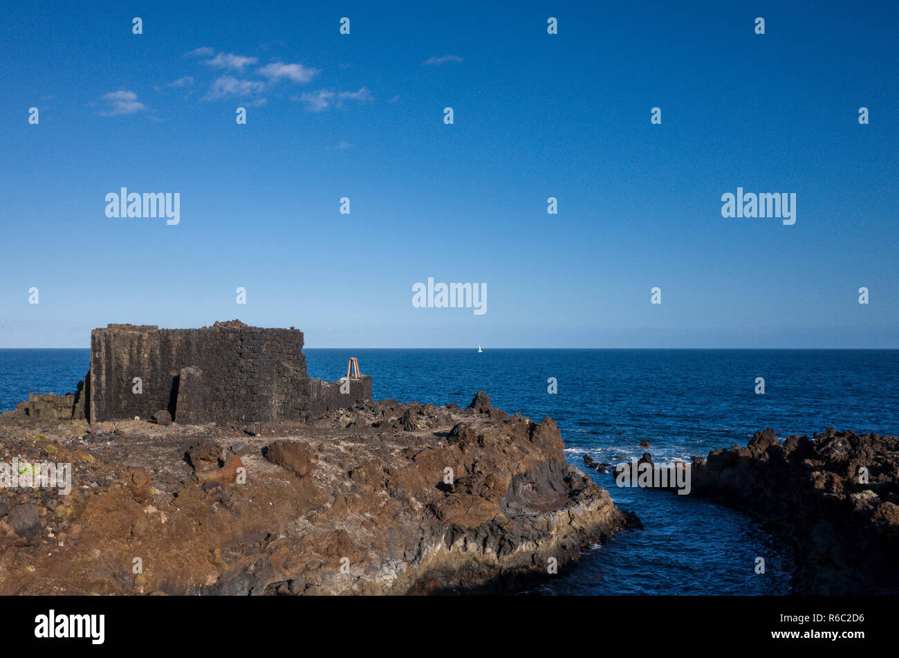 Shoreline, Los Cancajos.  La Palma.  The lava rock coastal landform that are typical of the island.  The remains of an old tower remain on a piece of land mass protruding into the ocean. Stock Photo