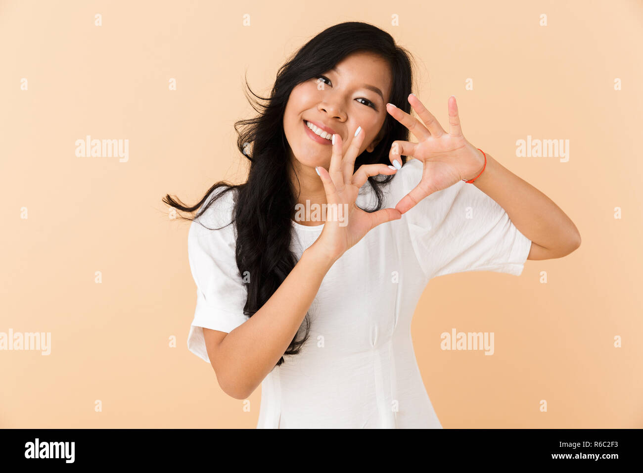 Portrait of a smiling young asian woman isolated over beige background ...