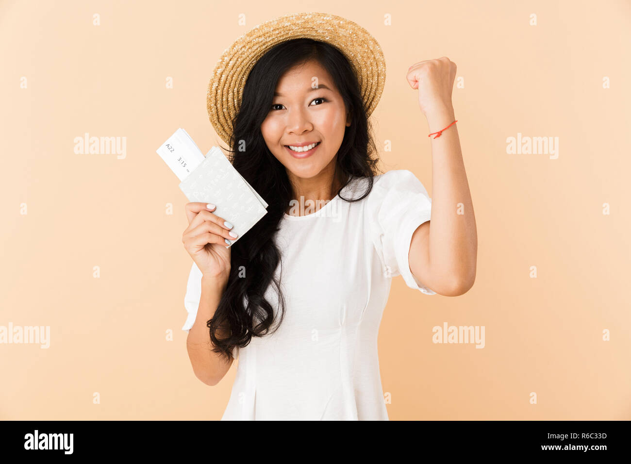 Portrait of a happy asian girl in summer hat isolated over beige ...