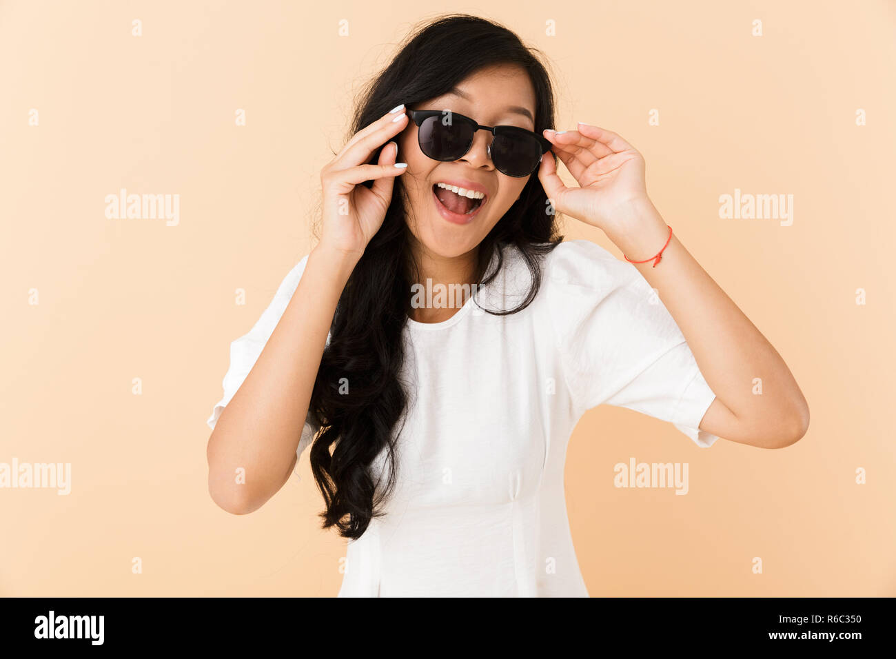 Image of a happy asian woman posing isolated over beige wall background ...