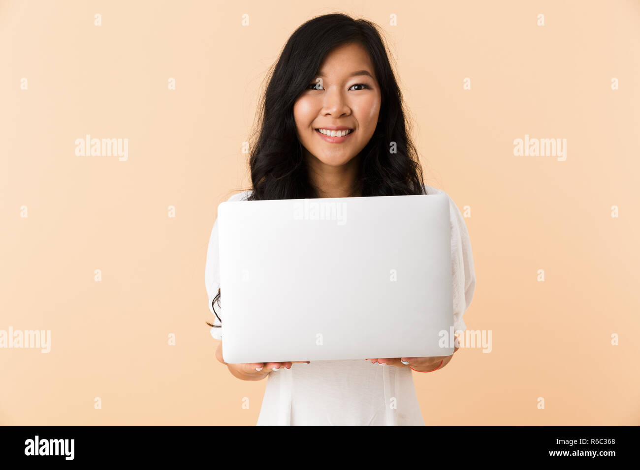 Image of a happy asian woman posing isolated over beige wall background ...
