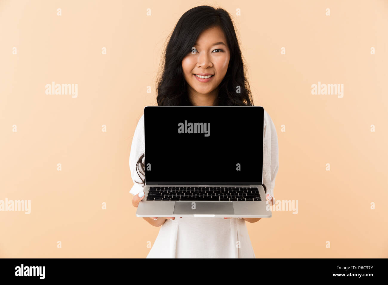 Portrait of a happy young asian woman isolated over beige background ...