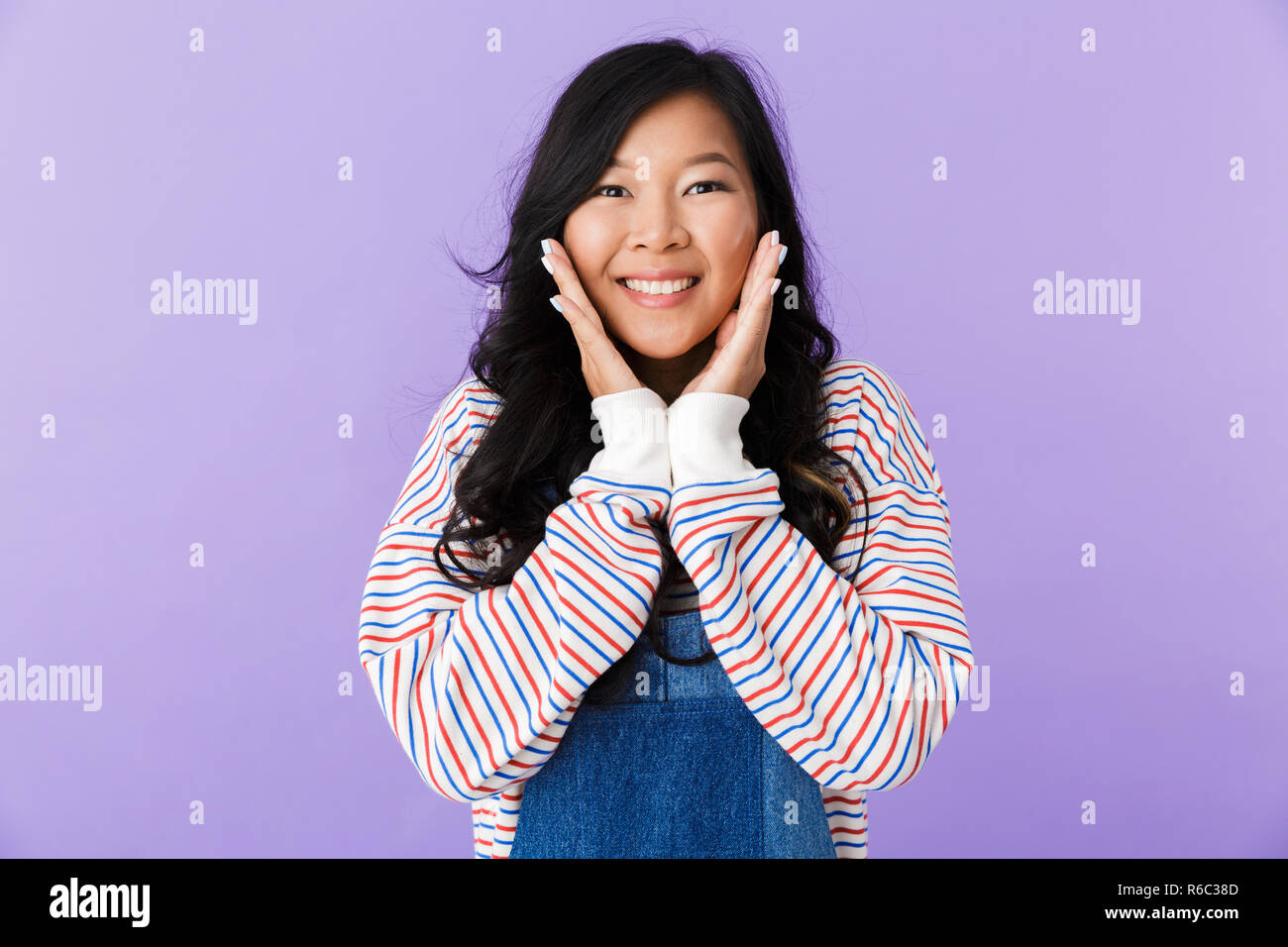 Portrait of a smiling young asian woman isolated over violet background ...