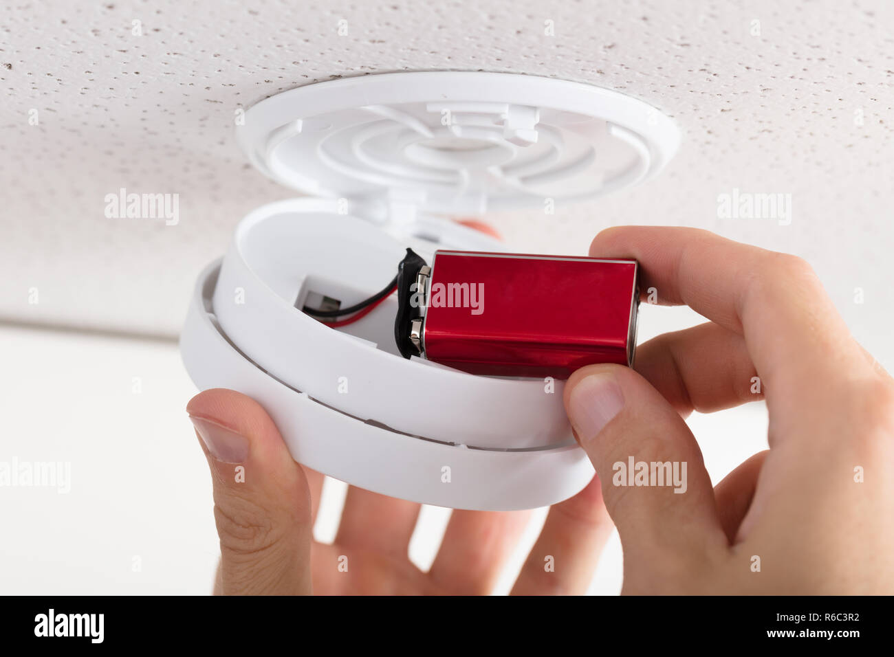 Person's Hand Inserting Battery In Smoke Detector Stock Photo