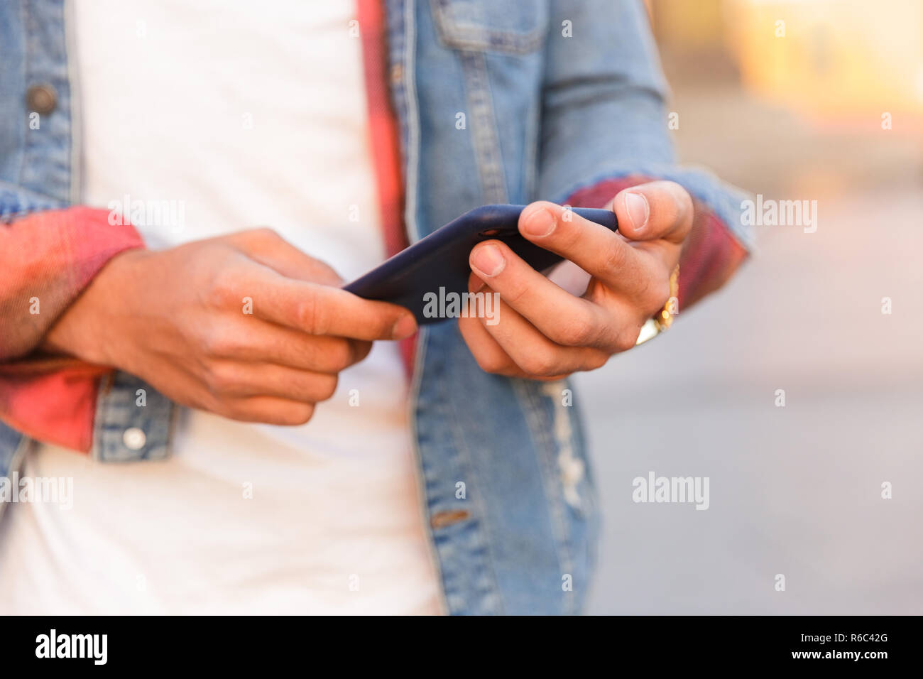 Cropped photo of handsome young guy walking outdoors using mobile phone. Stock Photo