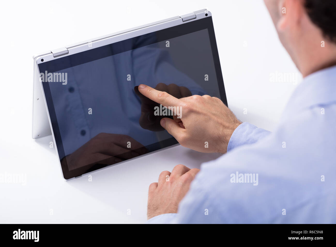 Man Touching Hybrid Laptop Screen With Finger Stock Photo