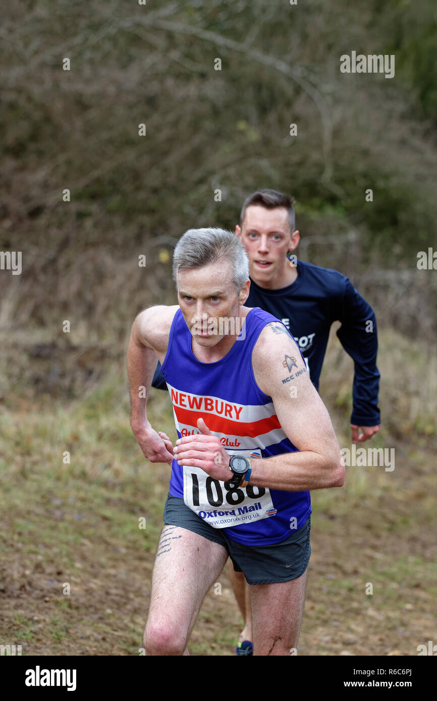 Male athlete running up a steep hill during the Oxfordshire Cross Country League event at Cirencester Park Stock Photo