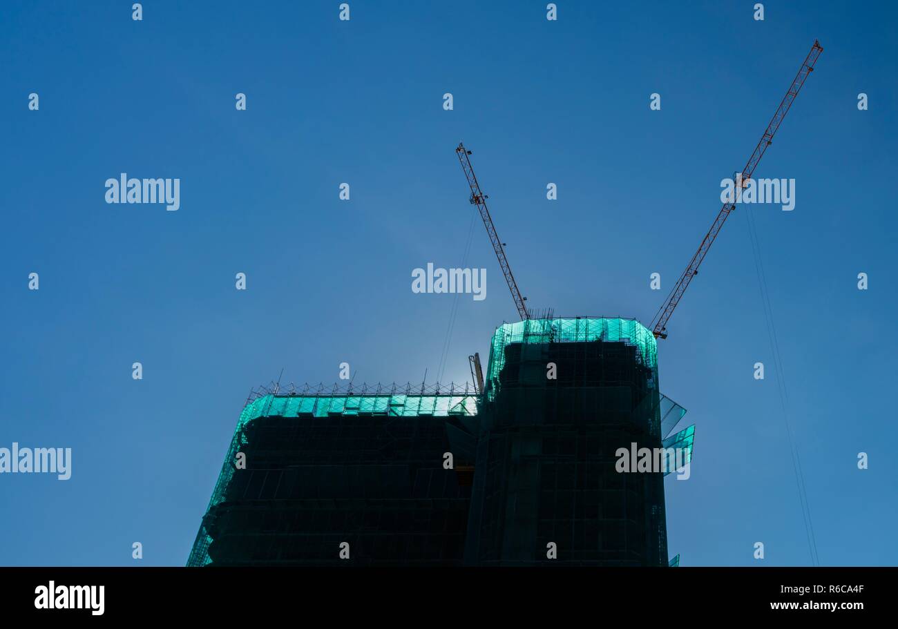 Cranes in operation over a construction site with clear blue skies in Vietnam. Stock Photo