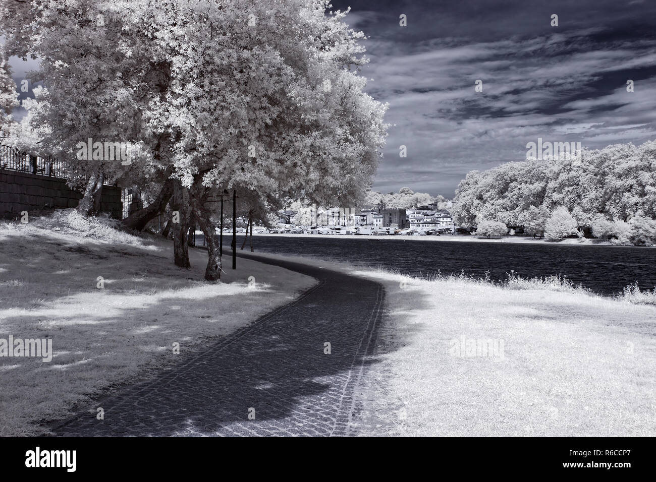 Lima river bank in a spring sunny afternoon seeing the medieval city of Ponte de Lima in the background. North of Portugal. Infrared toned blue. Stock Photo