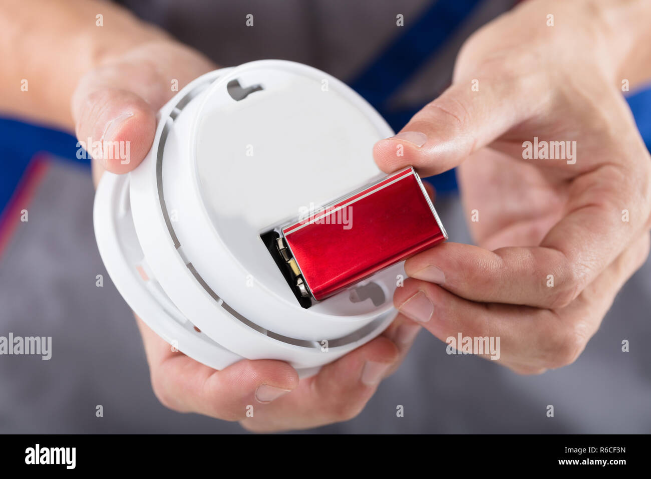 Person's Hand Inserting Battery In Smoke Detector Stock Photo