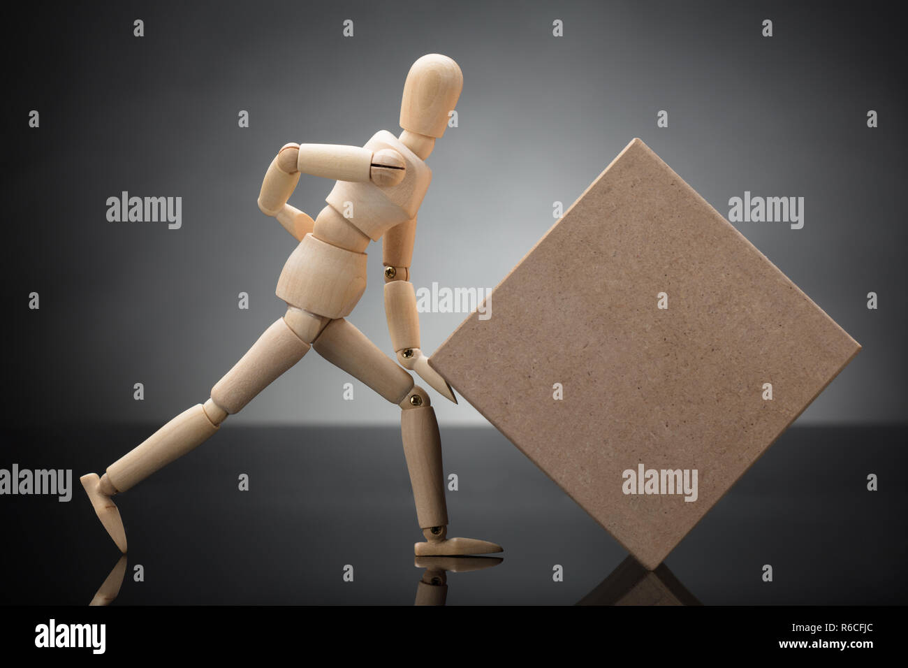 Wooden Dummy Lifting Cardboard Box Suffering From Back Pain Stock Photo