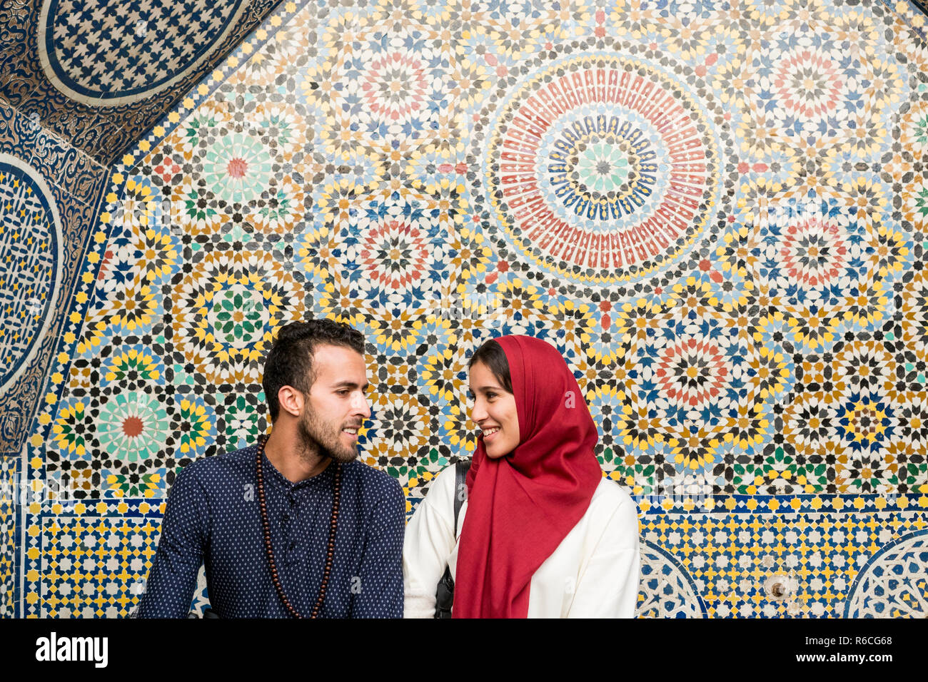 Young Muslim couple in relationship talking and smiling in front of arabesque oriental decoration Stock Photo