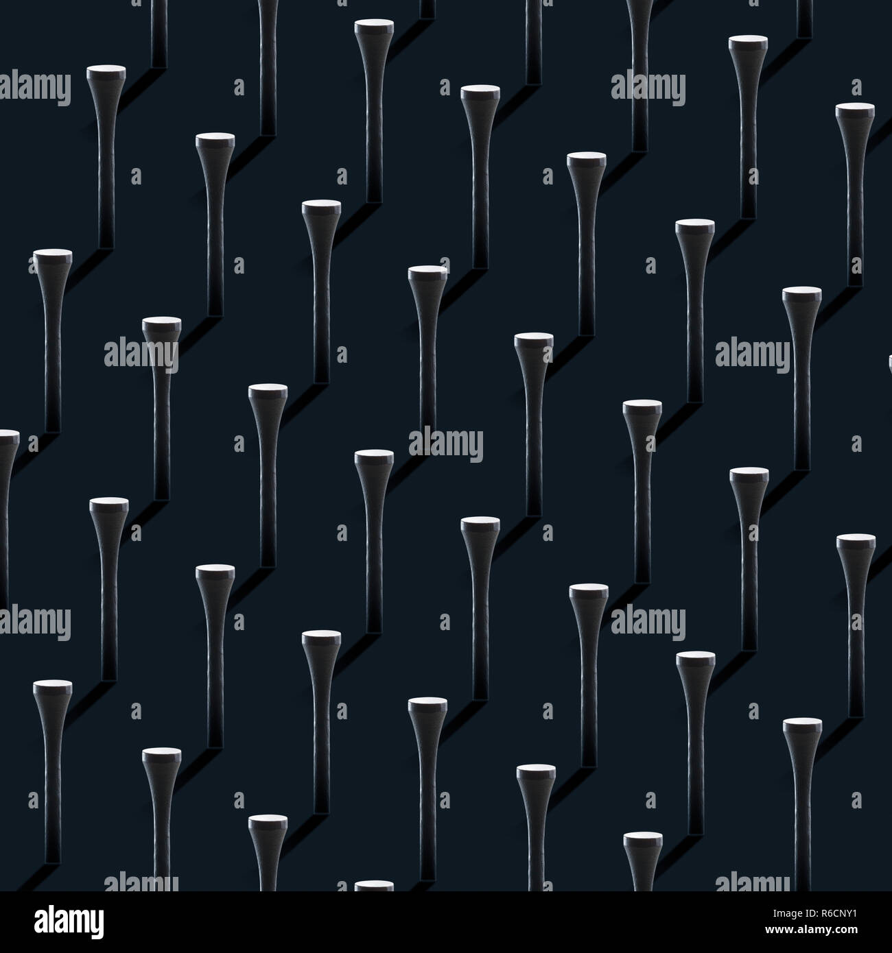 Ordered monochrome design of golf tees in line with dark background Stock Photo
