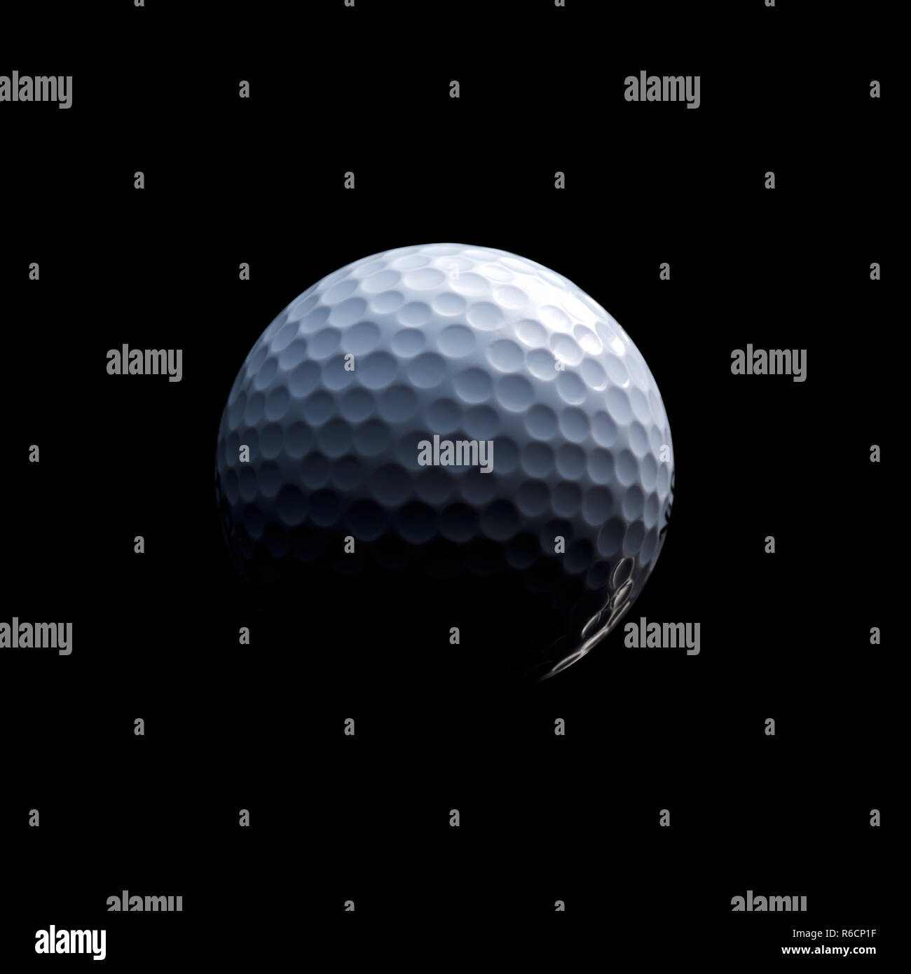 Detailed close of white dimpled golf ball in shadow, black background Stock Photo