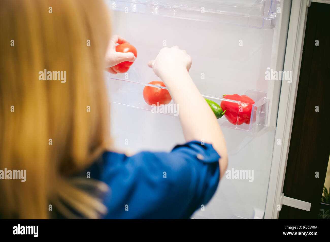 Housewives hand arranges purchased vegetables in the refrigerator Stock Photo