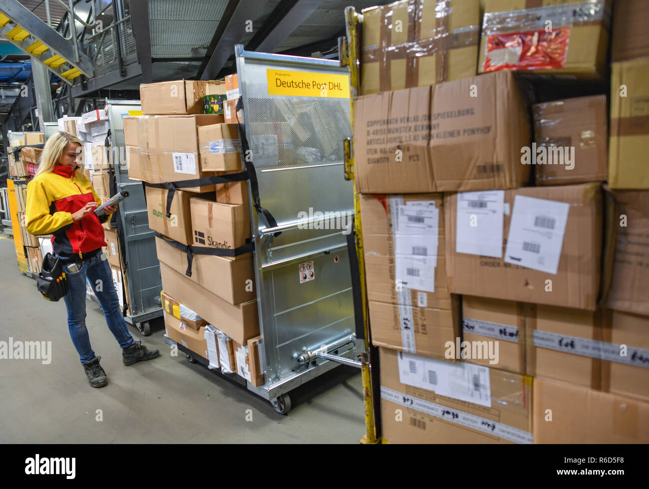 05 December 2018, Brandenburg, Rüdersdorf: Sandra Heller, employee at the DHL-Paketzentrum, checks parcels on a transport trolley. Let's get on with the parcels and packages: For the employees of parcel centres, it's time to roll up their sleeves again. For example at the DHL location in Rüdersdorf, Brandenburg (Märkisch-Oderland). Up to 550,000 parcels are processed here every day before Christmas. This year, the volume of consignments is again around ten percent higher than in the previous year. Photo: Patrick Pleul/dpa-Zentralbild/ZB Stock Photo