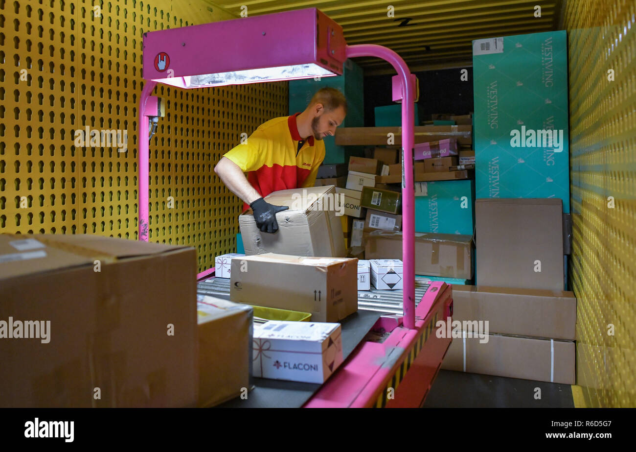 05 December 2018, Brandenburg, Rüdersdorf: Matthi Lippert, employee at DHL-Paketzentrum, stacks shipments from a conveyor belt into a truck. Let's get on with the parcels and packages: For the employees of parcel centres, it's time to roll up their sleeves again. For example at the DHL location in Rüdersdorf, Brandenburg (Märkisch-Oderland). Up to 550,000 parcels are processed here every day before Christmas. This year, the volume of consignments is again around ten percent higher than in the previous year. Photo: Patrick Pleul/dpa-Zentralbild/ZB Stock Photo