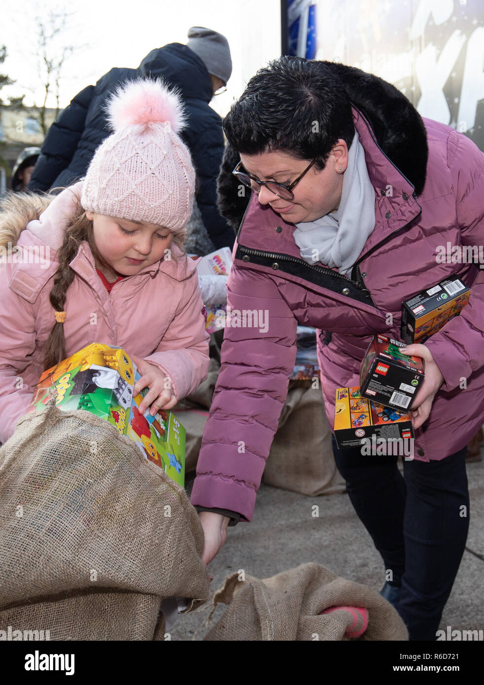 05 December 2018, Lower Saxony, Osnabrück: Birgit Beylich (r), head of the Osnabrück site of the Landesaufnahmebehörde (LAB), distributes toy presents to refugee child Chayma (7) from Syria. The Christmas presents will be distributed by a Christmas truck ('x-mas Express') to refugee children on the grounds of the Landesaufnahmebehörde. Together with Janina Martig Logistics, the Til Schweiger Foundation collects gifts for disadvantaged children. Photo: Friso Gentsch/dpa Stock Photo