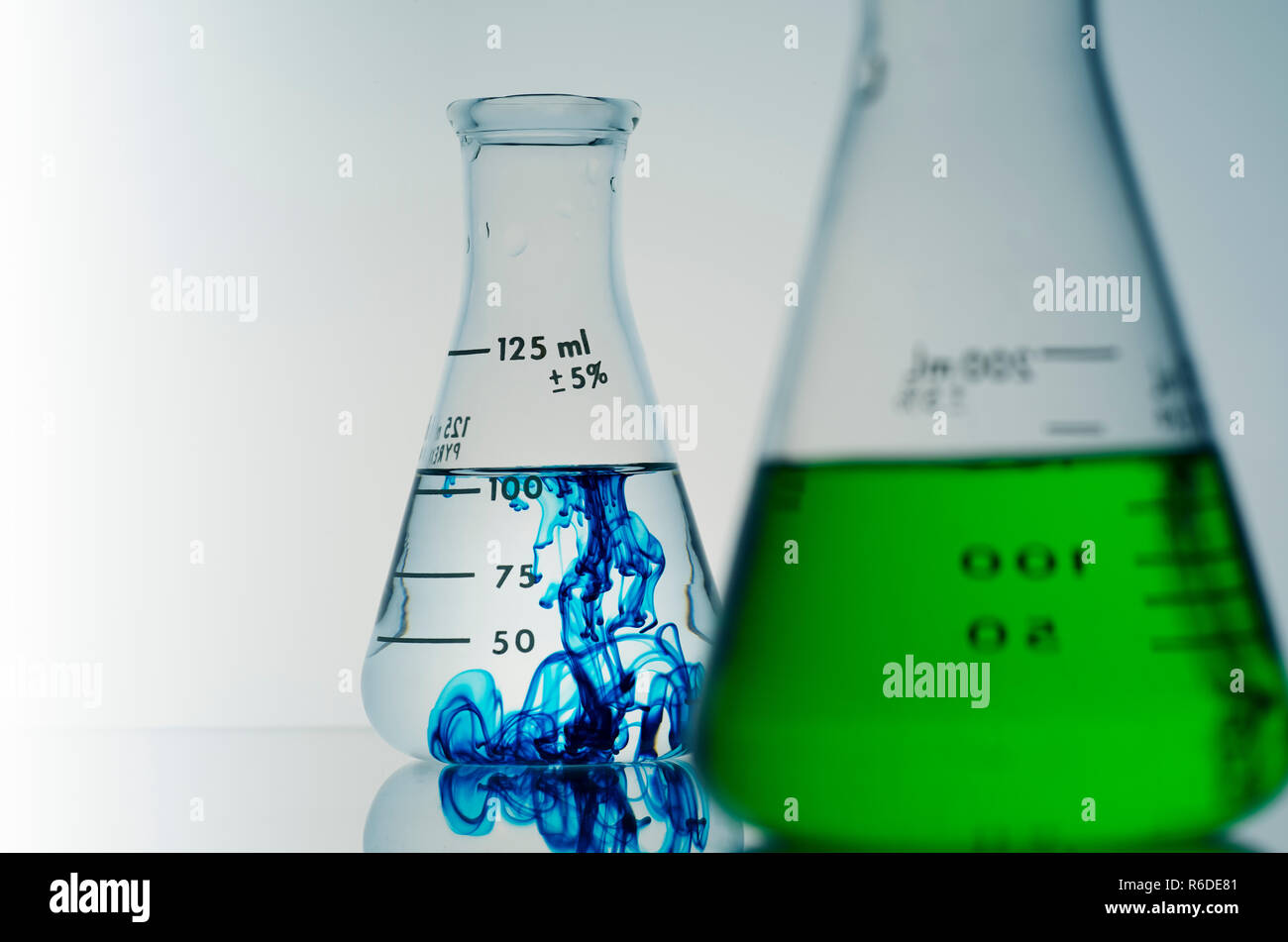 Two conical flasks containing green and blue liquids Stock Photo